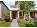 Inviting two-story brick home with front lawn, covered porch, balcony, and lush landscaping at 1265 S Sherman St, Denver, CO 80210