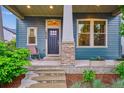 Inviting front porch with blue siding, stone accents, and a cozy seating area at 10360 E 57Th Pl, Denver, CO 80238