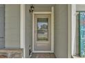 Close-up of the front door featuring a storm door, sidelights, and stylish hardware for a warm and welcoming entrance at 47349 Lily Ave, Bennett, CO 80102