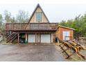 A-frame home featuring a two-car garage, wooden deck, and wood storage at 8691 S Warhawk Rd, Conifer, CO 80433