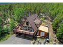 Aerial view of A-frame home with deck and shed, surrounded by dense trees, and a driveway at 8691 S Warhawk Rd, Conifer, CO 80433