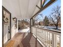 Inviting covered front porch with stained wood floors and white railing is perfect for relaxing and enjoying the outdoors at 1960 S Franklin St, Denver, CO 80210