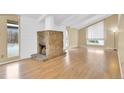 Open-concept living room featuring a stone fireplace, hardwood floors, and large windows at 2978 Robb Cir, Lakewood, CO 80215