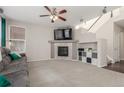Cozy living room featuring a fireplace, ceiling fan, plush gray sofa, and staircase access at 10438 Olathe Way, Commerce City, CO 80022