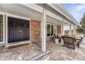 Inviting covered porch with brick flooring, seating, and a view of the front yard at 4650 E Links Pkwy, Centennial, CO 80122