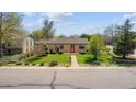 Charming single-story home featuring mature trees, landscaped yard and inviting walkway to front door at 998 S Leyden St, Denver, CO 80224