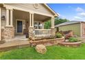 Inviting front porch with stone pillars and a quaint seating area surrounded by landscaping at 1831 Ashford Cir, Longmont, CO 80504