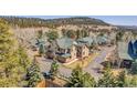 An aerial shot of the property with a green roof surrounded by lush trees and mountain views at 1294 Red Lodge Dr, Evergreen, CO 80439