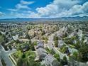 Panoramic aerial shot of a neighborhood nestled among lush trees with mountain views in the distance at 5172 S Cody Ct, Littleton, CO 80123