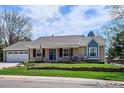 This charming home features a well-manicured lawn and inviting front porch with brick and colorful plants at 5172 S Cody Ct, Littleton, CO 80123