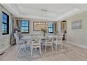 Elegant dining room with a large table, white chairs, tray ceiling, and scenic views through the windows at 6860 S Yantley Ct, Aurora, CO 80016
