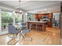 Open-concept kitchen and dining area with stainless appliances, island seating, and a modern chandelier at 7844 S Eudora Cir, Centennial, CO 80122