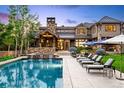 Inviting backyard pool area with lounge chairs, umbrellas, and a stone waterfall feature at 5 Random Rd, Cherry Hills Village, CO 80113