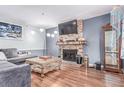 Cozy living room with a brick fireplace, plush gray sectional, and wood-look flooring at 18206 E Loyola Dr, Aurora, CO 80013