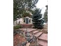 Inviting front entrance with brick steps leading to a modern, light colored home with large windows and mature trees at 1425 Autumnwood Ln, Evergreen, CO 80439