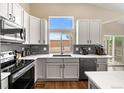 Modern kitchen featuring white cabinetry, stainless steel appliances, and a window overlooking the backyard at 2209 Lupine Pl, Erie, CO 80516