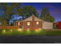 Charming brick home features a well-maintained front yard and mature trees at dusk at 3102 N Columbine St, Denver, CO 80205