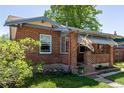 Charming brick home with a covered porch, flag, and beautiful landscaping at 2564 S Acoma St, Denver, CO 80223