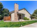 Inviting home exterior showcasing a brick chimney, covered entry, and verdant lawn at 10836 W Evans Ave # 29, Lakewood, CO 80227
