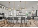 Bright open kitchen has large island with seating, stainless steel appliances and decorative pendant lights at 8023 Gore Creek Ln, Littleton, CO 80125