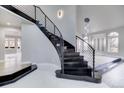 Modern curved staircase with metal railing and marble flooring at 16521 E Easter Way, Foxfield, CO 80016