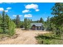 Exterior of home with gravel driveway and natural, wooded surroundings at 10411 Dowdle Dr, Golden, CO 80403