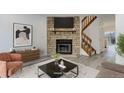 Cozy living room with a stone fireplace, modern decor and wood stairs leading to upper level at 11973 E Kepner Dr, Aurora, CO 80012