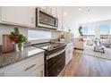 Modern kitchen with stainless steel appliances and granite countertops flows into a bright living area at 22093 E 38Th Pl, Aurora, CO 80019