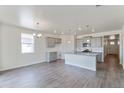 Open-concept kitchen with gray cabinets, granite countertops, stainless steel appliances, and wood flooring at 13457 Valentia St, Thornton, CO 80602