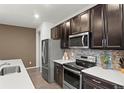 Modern kitchen boasts stainless steel appliances, stylish backsplash, and ample dark wood cabinetry at 11440 E 26Th Ave, Aurora, CO 80010