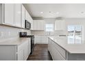 Bright kitchen with white cabinets, stainless steel appliances, a large island, and hardwood floors at 18958 E 94Th Pl, Commerce City, CO 80022