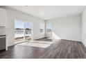 Open-concept living room with hardwood floors, large windows, and sliding glass doors to the backyard at 18958 E 94Th Pl, Commerce City, CO 80022