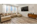 Bright living room with a comfortable beige sectional sofa, large TV, and wood-style flooring at 23920 E 34Th Ave, Aurora, CO 80019