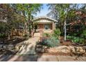 Inviting home with brick accents and a landscaped front yard featuring stone accents and mature trees at 1633 Gaylord St, Denver, CO 80206
