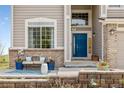 Close-up of a inviting front porch with seating area, blue accents, and brick accents at 6950 Blue Mesa Ln, Littleton, CO 80125