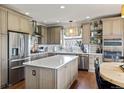 Well-lit kitchen featuring a large island, stainless steel appliances, and light brown cabinetry at 6950 Blue Mesa Ln, Littleton, CO 80125