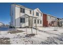 Two-story white house with gray accents, snowy yard, and other houses in the background at 2916 Oxley St, Strasburg, CO 80136