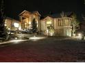 Night view of an elegant home with stone accents and professional landscaping and lighting at 580 Summer Mist Cir, Castle Rock, CO 80104