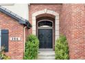 Charming front door framed by brick archway, lush greenery and decorative wreaths at 286 Claymoor Ct, Castle Pines, CO 80108