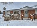 Brick ranch home with snow-covered landscaping and a spacious front yard at 7025 Newland St, Arvada, CO 80003