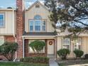 Two-story townhome with brick and siding, featuring a manicured lawn and mature trees at 9618 W Chatfield Ave # E, Littleton, CO 80128