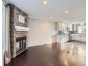 Open living room with dark hardwood floors, a stone fireplace, and adjacent kitchen at 9618 W Chatfield Ave # E, Littleton, CO 80128