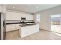 Modern kitchen with white cabinets, a center island, stainless steel appliances, and a sliding door to the backyard at 16686 E 110Th Ave, Commerce City, CO 80022