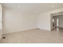 Spacious living room featuring light wood floors and a doorway to the entry and staircase at 16686 E 110Th Ave, Commerce City, CO 80022