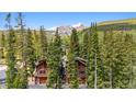 Exterior showcasing a rustic home nestled among tall trees with scenic mountain views at 960 Whispering Pines Ln, Breckenridge, CO 80424