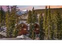 Exterior view of two beautiful cabin-style homes with snow-covered rooftops, surrounded by lush trees and majestic mountains at 960 Whispering Pines Ln, Breckenridge, CO 80424