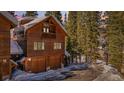 Charming two-story cabin-style home with a two car garage nestled among lush, mature trees and snow covered landscape at 960 Whispering Pines Ln, Breckenridge, CO 80424