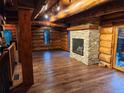 Cozy living area with stone fireplace, log walls, and gleaming hardwood floors at 733 Rainbow Rd, Idaho Springs, CO 80452