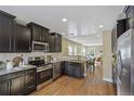 Well-appointed kitchen with stainless steel appliances, dark cabinetry, and hardwood floors flowing into the dining area at 1552 Hudson St, Denver, CO 80220