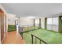 Bright living room featuring vintage green carpet, large windows, and a decorative railing at 8487 Yarrow Ct, Arvada, CO 80005